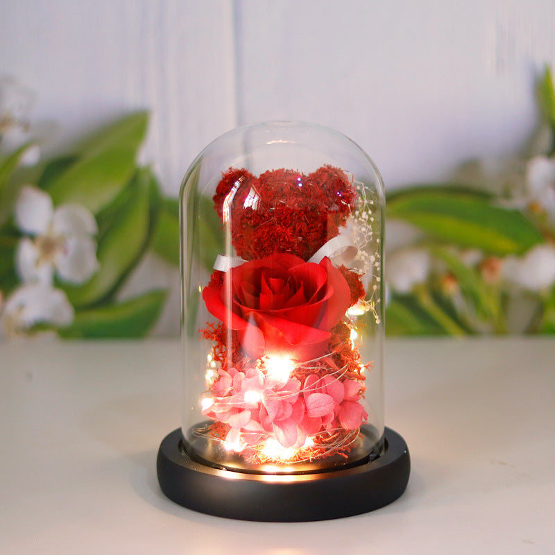 Teddy bear with eternal rose under glass dome with warm LED light