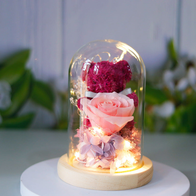 Teddy bear with eternal rose under glass dome with warm LED light