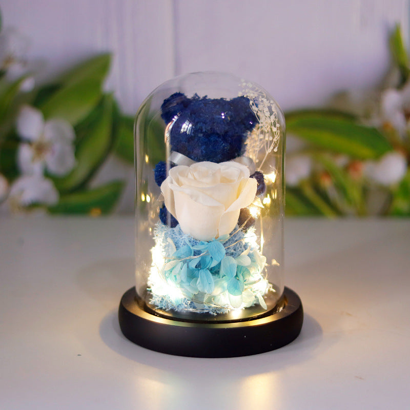 Teddy bear with eternal rose under glass dome with warm LED light