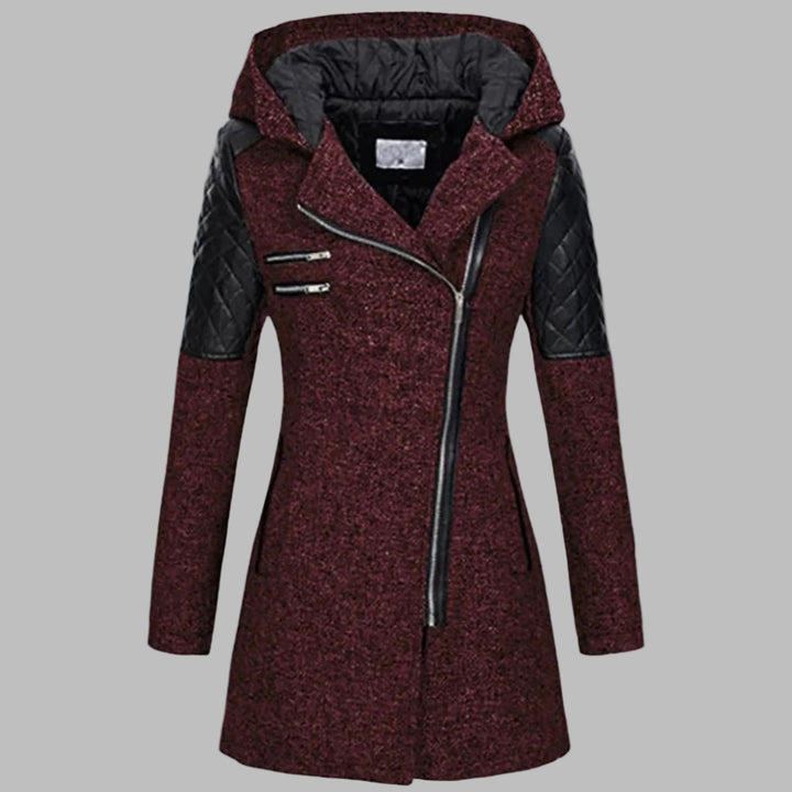 Donkerrode dames winterjas met capuchon, asymmetrische rits en zwarte leren accenten. Stijlvolle en warme jas voor koude winterdagen.