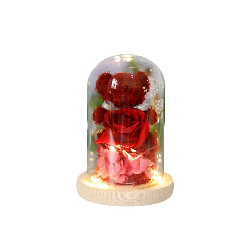 Teddy bear with eternal rose under glass dome with warm LED light