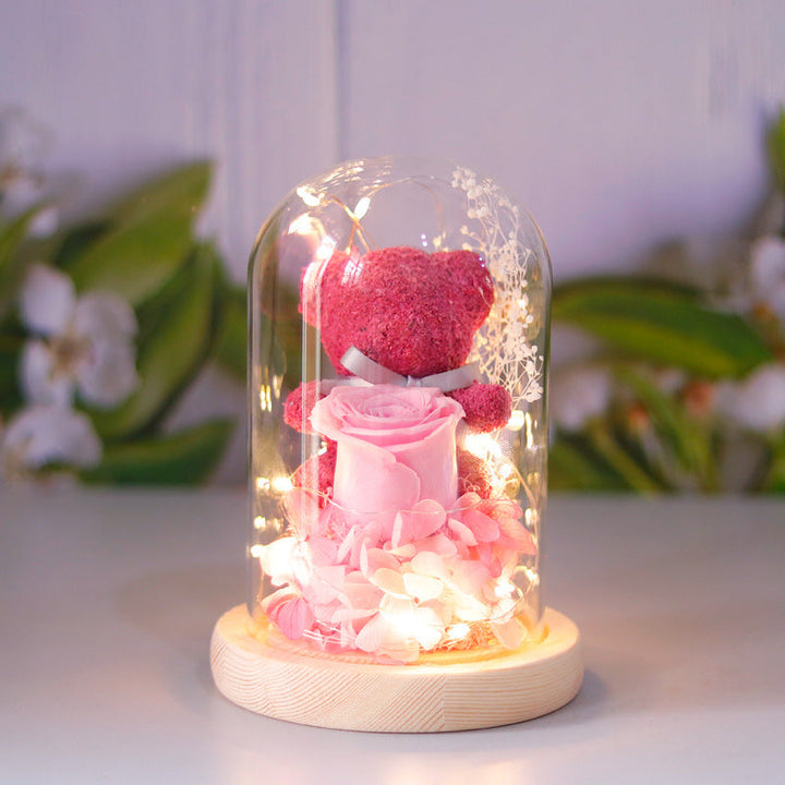 Teddy bear with eternal rose under glass dome with warm LED light