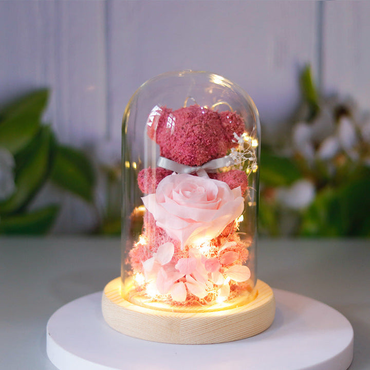 Teddy bear with eternal rose under glass dome with warm LED light